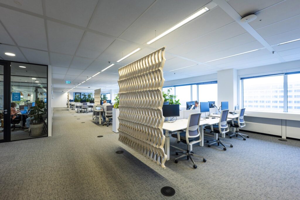 Moderne kantoortuin aan de Johan Huizingalaan met open werkplekken, glazen vergaderruimte en een opvallend decoratief scheidingselement.